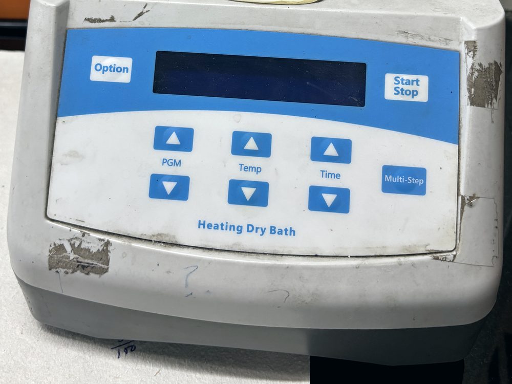 The worn control panel of a heating dry bath, its keypad scuffed from years of use.